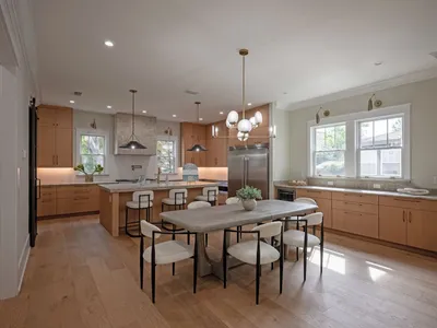 Dining area open to the kitchen under designer pendant lighting