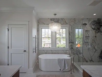 Spa-style primary bath with freestanding soaking tub and marble surround