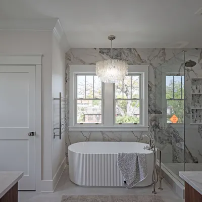 Spa-style primary bath with freestanding soaking tub and marble surround
